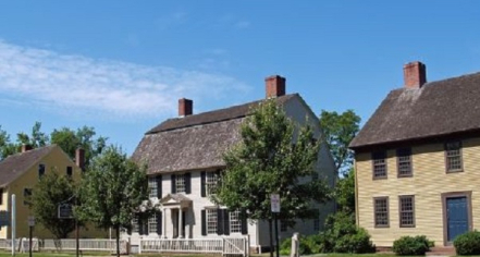 Image Of Two Yellow Houses And One White House Side-by-side. Each House Has A Brown Roof And Chimneys. 