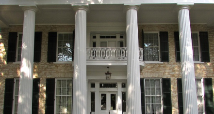 Image Of The Facade Of A Two-story House With Six White Ionic Pillars And Black Shutters On The Windows.