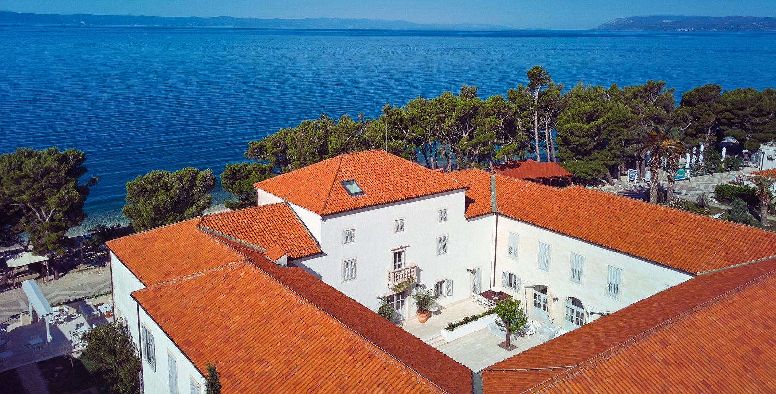 Image of exterior aerial view of courtyard backdropped by Adriatic Sea at Heritage Hotel Kaštelet, 1766, a Member of Historic Hotels Worldwide since 2024 in Tučepi, Croatia