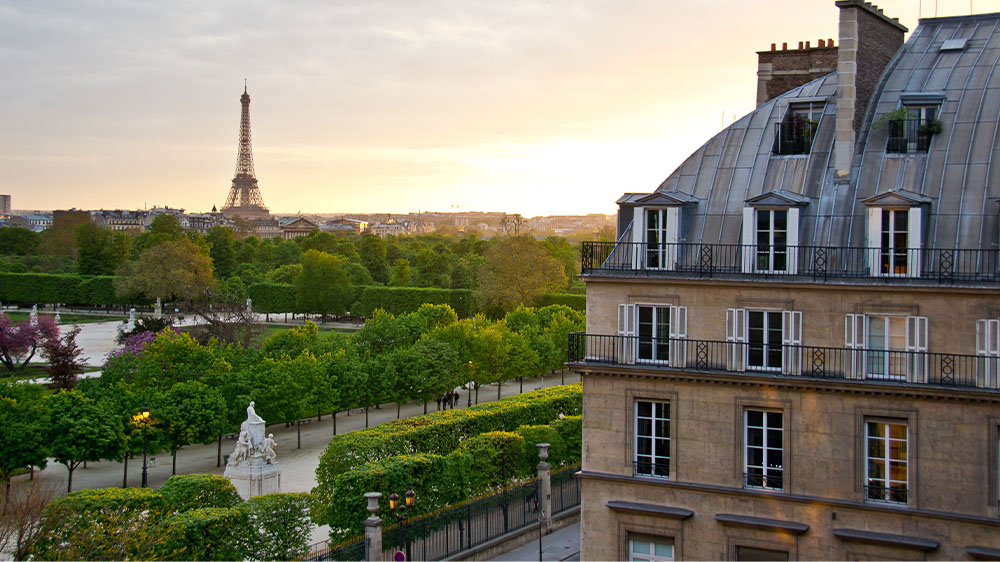 Daytime exterior of Hotel Regina in Paris, France with Eiffel Tower in the background.